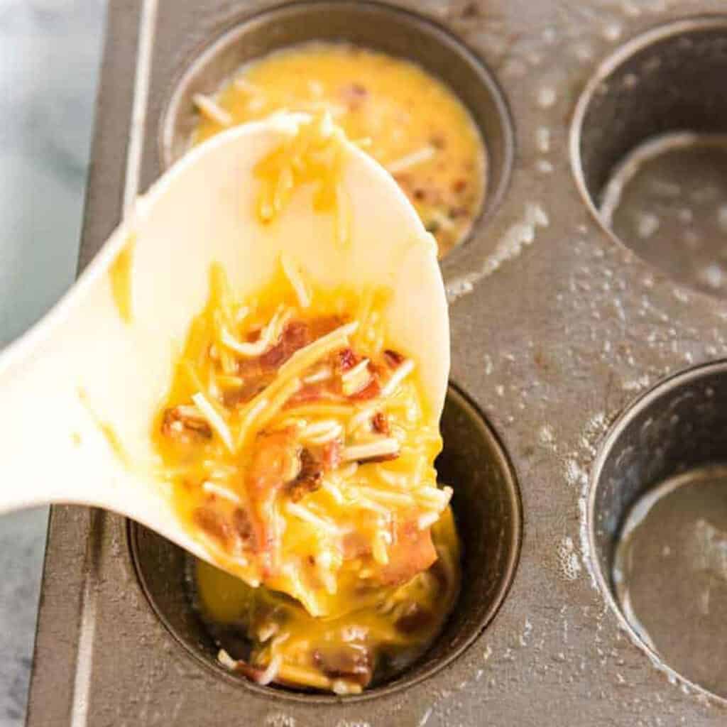 spooning egg mixture into muffin tin