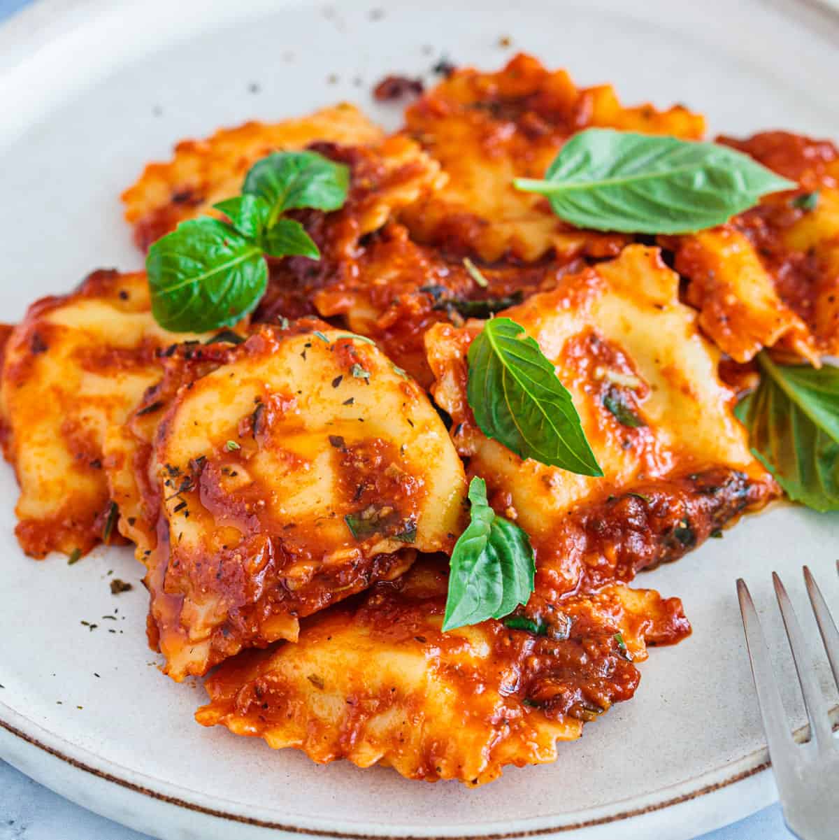 ravioli and meat sauce on white plate with fork